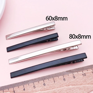 Flat lay of silver and black metal duckbill hair clips in 60x8mm and 80x8mm sizes