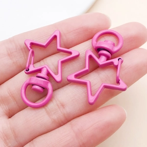 Macro view of two bright pink star-shaped zinc alloy lobster clasps held in a palm