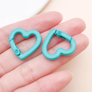 Close-up of two cyan heart-shaped lobster clasps for DIY jewelry and bag charms
