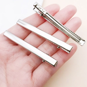 Detailed macro view of silver duckbill hair clips with Korea engraved on metal surface