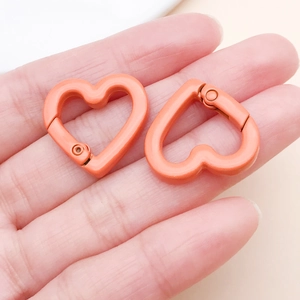 Close-up of orange heart-shaped carabiner clips held in hand for DIY jewelry and bag charms