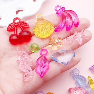 Colorful mixed acrylic pendants including cherry and heart shapes held in hand