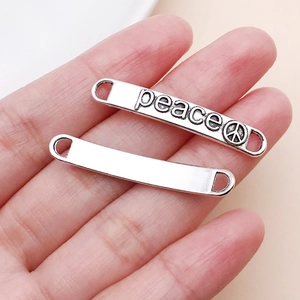 Makroaufnahme von silbernen rechteckigen Metallanhängern mit Peace-Zeichen und Text