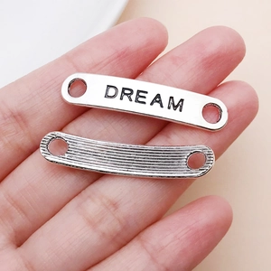Detail von silbernen Metallanhängern mit Dream-Gravur und strukturierter Oberfläche für Schmuck