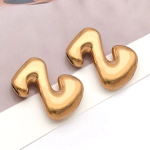 Makroaufnahme von poliertem Gold-S-Anhänger mit seitlichen Löchern für DIY-Schmuck