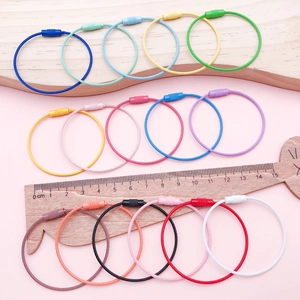 Colorful steel wire keychains with screw locks shown on a pink wooden measurement board