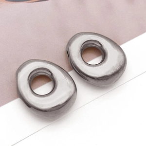 Makro-Detail von silbernen Buchstaben-Anhängern mit polierter Oberfläche für DIY-Schmuck