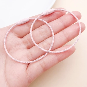 Pink stainless steel wire key ring being held by hand to show size and threaded screw closure
