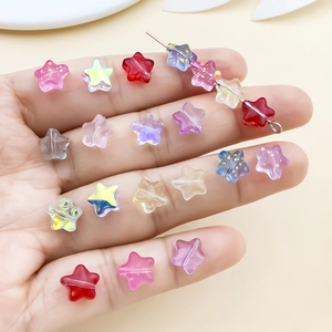 Hand holding colorful star-shaped glass beads with gold powder for DIY jewelry making