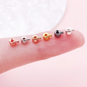 Miniature copper jewelry positioning beads in six metallic colors shown on a fingertip