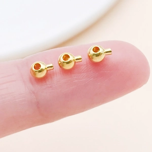 Macro view of tiny gold-plated copper crimp beads for DIY jewelry making accessories
