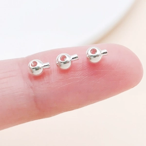 Macro shot showing small silver copper crimp beads for DIY jewelry making on a finger