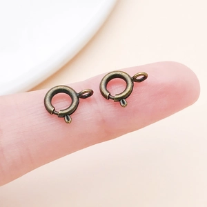 Macro shot of two vintage bronze spring ring clasps on a fingertip for size comparison