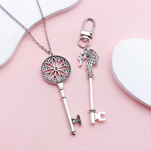 Antique silver key pendants with seahorse and hollow flower designs on pink background