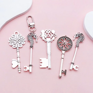 Detailed view of five vintage silver-plated heart and key pendants on a soft pink background