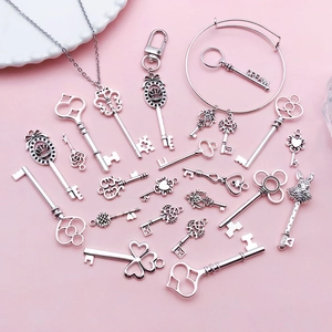 Antique silver vintage key pendants with heart and crown patterns on pink background