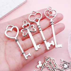 Vintage silver hollow heart key pendants held in hand for DIY jewelry making