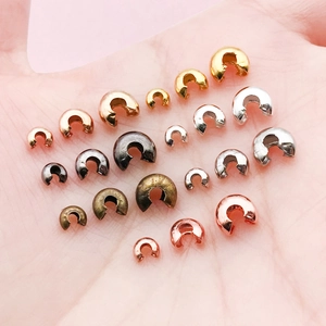 Copper crimp bead covers for DIY jewelry in gold and silver plating on a palm