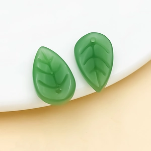 Detail of green leaf-shaped glass charms with golden veins for DIY hair jewelry making