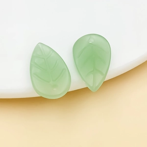 Detail shot of translucent pale green leaf charms with delicate gold-edged vein textures