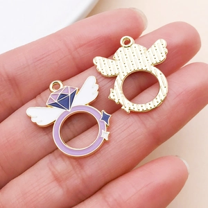 Macro shot of purple alloy heart charm with wings showing glossy enamel and gold back