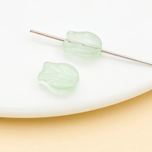 Macro shot of translucent light green tulip glass beads showing petal details and thru-hole