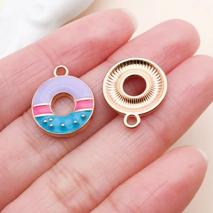 Macro detail of double-sided donut charms with purple enamel and rose gold finish
