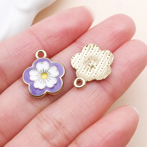 Macro shot of purple flower pendants with enamel finish and gold metal back textures