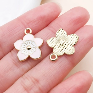 Detailed macro view of pink cherry blossom enamel pendants for DIY jewelry making