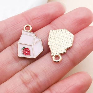Detail of pink strawberry milk box charms with golden alloy base and enamel finish