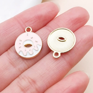 Macro shot of pink enamel doughnut charm with rainbow sprinkles and golden metal backing