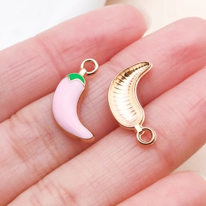 Macro shot of pink enamel chili pepper charms with gold trim and textured back details
