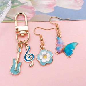 Detail of light blue guitar charms and butterfly earrings with gold alloy plating