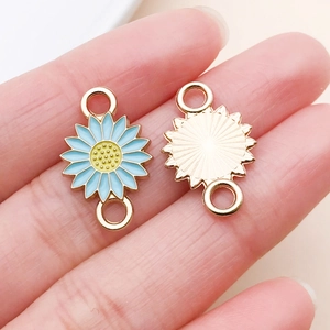 Detailed macro view of light blue enamel daisy charm with gold metal finish and dual loops