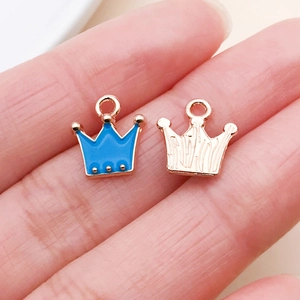 Close-up of crown-shaped alloy pendants in blue and rose gold for DIY jewelry