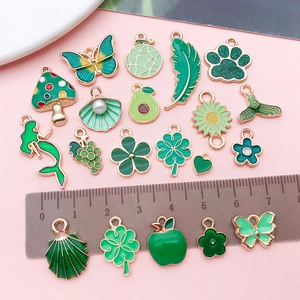 Macro shot of assorted green enamel charms with golden alloy edges and scale ruler