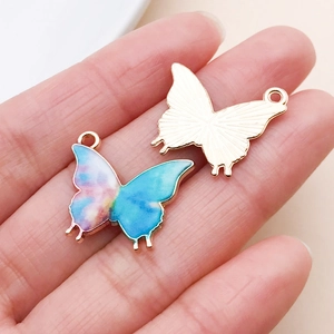 Detail of blue and pink enamel butterfly charms with golden metal back for DIY jewelry