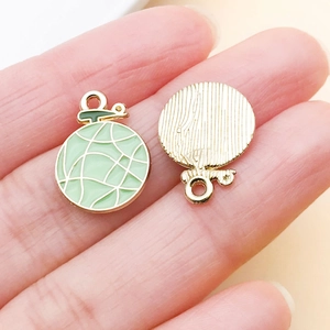 Detail of green melon alloy charms with enamel finish and textured gold back for DIY jewelry