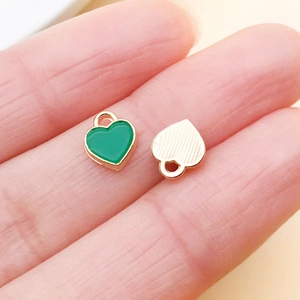 Close-up of green heart enamel charms with gold plating for DIY jewelry making and crafts