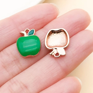 Macro detail of apple charm featuring green enamel front and rose gold textured metal back