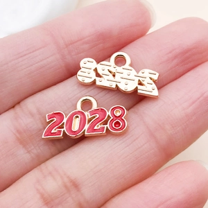 Makroaufnahme der 2028 Jahr-Anhänger in roter Emaille und Gold-Finish auf der Handfläche