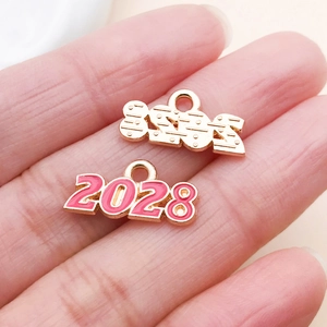 Detailansicht der kleinen 2028 Zahlenanhänger in Gold und Pink für DIY-Schmuckzubehör