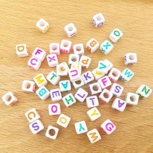 Close-up of 6mm acrylic alphabet cube beads with colorful letters on a wood background