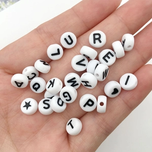 Close-up of 6mm white acrylic alphabet beads with black uppercase letters held in hand