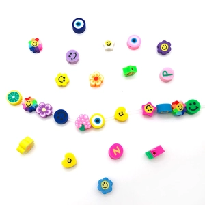 Vue à plat de perles colorées en pâte polymère avec fruits, sourires et œil maléfique
