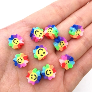 Détail de perles de fleurs colorées en pâte polymère avec smileys dans une main