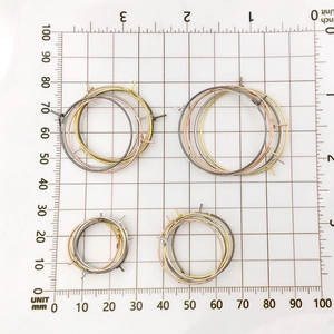 Macro shot of assorted metal DIY earring hoops on a millimeter measurement grid board