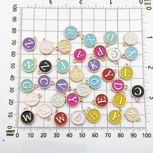 Close-up of colorful enamel alloy alphabet pendants with gold plating on a measuring grid
