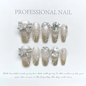 Faux ongles faits main avec base pailletée, pointes argentées et nœuds en strass 3D