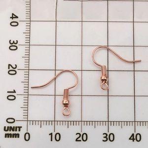 Detailed view of rose gold earring hooks with measurements on a scale for DIY crafts